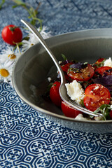 bowl of salad with tomatoes, feta cheese and basil on table