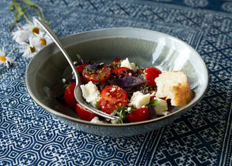 bowl of salad with tomatoes, feta cheese and basil on the table