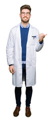 Young handsome scientist man wearing glasses smiling with happy face looking and pointing to the side with thumb up.