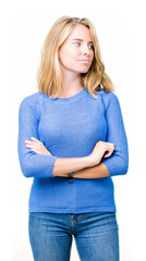 Beautiful young woman wearing blue sweater over isolated background smiling looking to the side with arms crossed convinced and confident