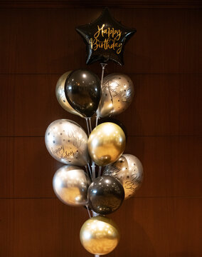 Close-up of a bunch of black and silver birthday in front of a wooden wall