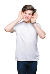 Fototapeta premium Young handsome man wearing casual white t-shirt over isolated background Trying to hear both hands on ear gesture, curious for gossip. Hearing problem, deaf
