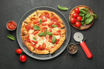 Delicious Margherita pizza, ingredients and cutter on black table, top view