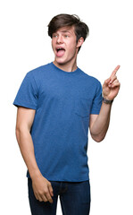 Naklejka premium Young handsome man wearing blue t-shirt over isolated background with a big smile on face, pointing with hand and finger to the side looking at the camera.