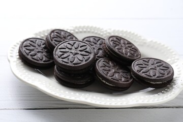 Many tasty sandwich cookies on white wooden table