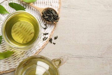 Refreshing green tea in cup, spoon and leaves on wooden table, flat lay. Space for text