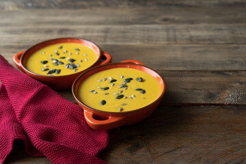 Two bowls of soup with seeds on top of a red cloth. Copy space.