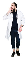 Doctor with long hair wearing medical coat and stethoscope shouting and screaming loud to side with hand on mouth. Communication concept.
