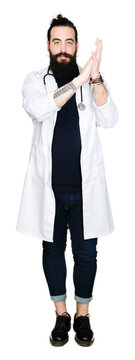 Doctor with long hair wearing medical coat and stethoscope Clapping and applauding happy and joyful, smiling proud hands together