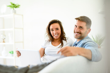 bearded husband cuddling affectionate wife on computer at home. Using laptop in living room.