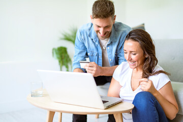 Fototapeta premium bearded husband cuddling affectionate wife on computer at home. Using laptop in living room.