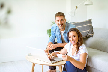 bearded husband cuddling affectionate wife on computer at home. Using laptop in living room.