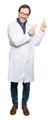 Middle age therapist wearing white coat smiling and looking at the camera pointing with two hands...