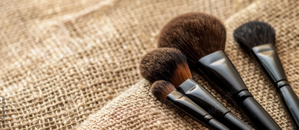 Poster Makeup brushes displayed on a beige fabric background with copy space image for custom designs, websites, and advertisements.