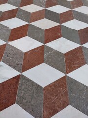 Abstract 3D background, optical illusion or deception. Vertical image. Diamond shaped stones. Subjective perception of bands, zigzag lines, cubes. White, red, gray marble Stones. Floor Admont Library