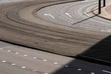 An image depicting a curving road with tram rails and directional arrows, highlighting elements of urban infrastructure and transportation within a city environment  in Rotterdam