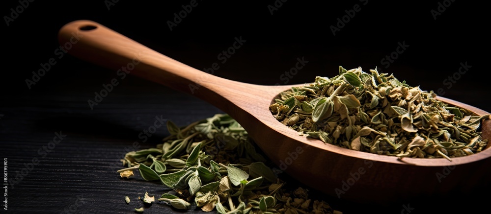 Poster a top-down view of dried oregano herbs in a wooden spoon against a black background with a close-up 