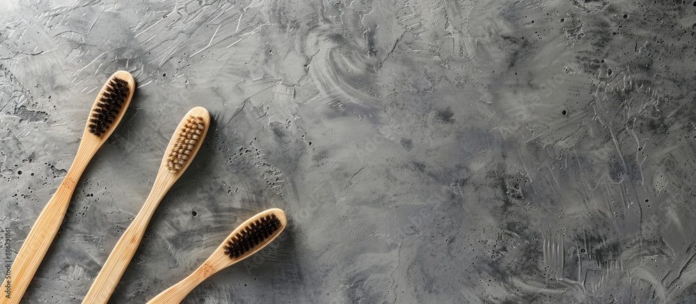 Poster Bamboo toothbrushes arranged on a gray stone surface with space for text or images, creating a minimalist bath background.
