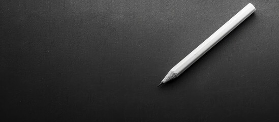 A white pencil on a black background, perfect for a back-to-school theme with plenty of copy space image.