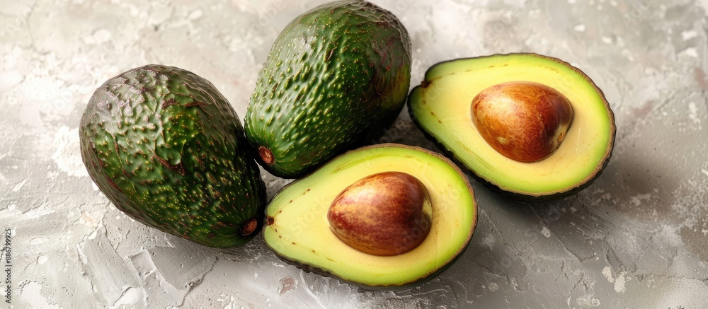 Poster Whole and sliced ripe avocados displayed from the top view on a white backdrop with ample copy space image.