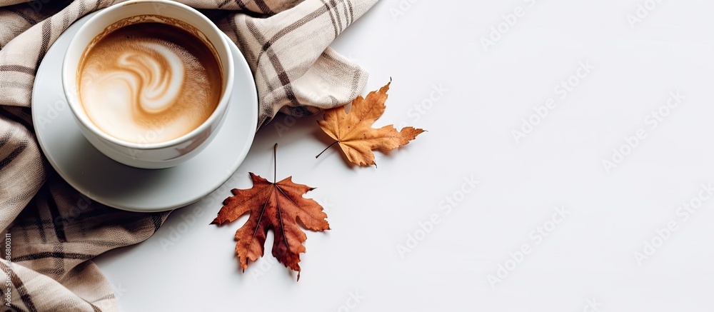 Poster a cup of coffee sits on a checkered scarf with a fallen leaf against a white background, offering pl
