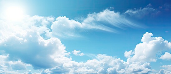 Sunny weather with bright blue sky and fluffy white clouds, ideal as a nature-themed background. The serene image portrays a heavenly landscape with ample space for text or design elements.