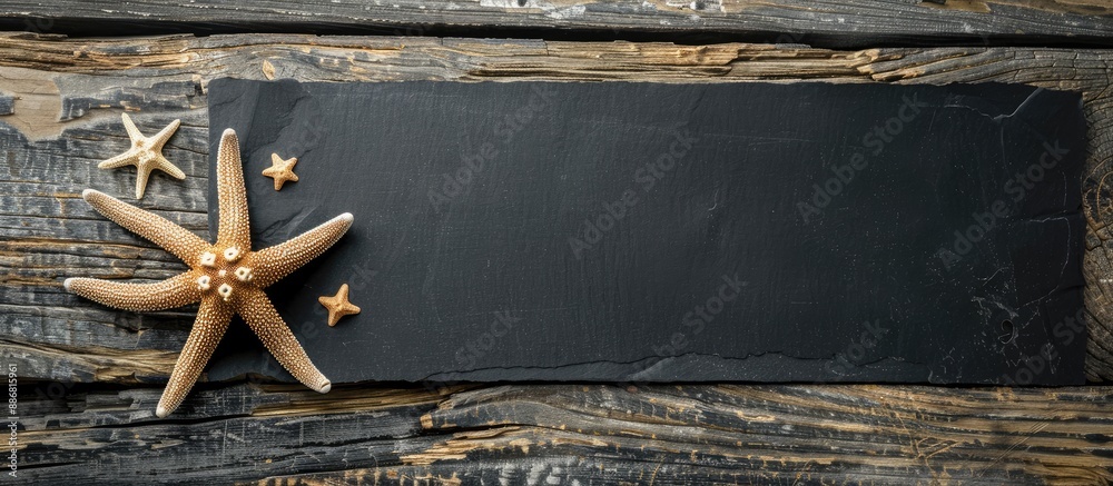 Aufkleber Flat lay composition featuring starfish on a rustic wooden surface with a blank black paper for copy space image.