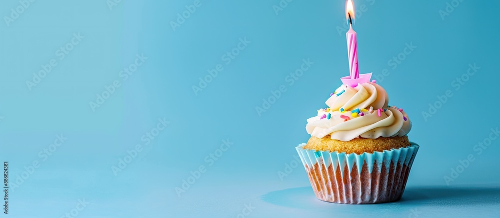 Poster a birthday cupcake with pink candles against a blue backdrop, ideal for adding text or graphics with