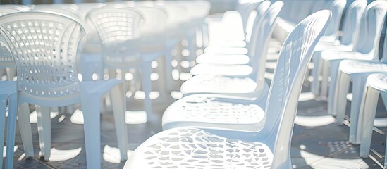 An array of neatly aligned white plastic chairs under the sun, seen from behind, offers a visual backdrop with space for adding text or images.