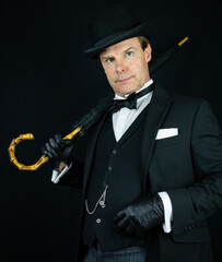 Elegant Vintage Gentleman in Dark Suit and Bowler Hat Holding Umbrella. Wealthy Upper Class English...