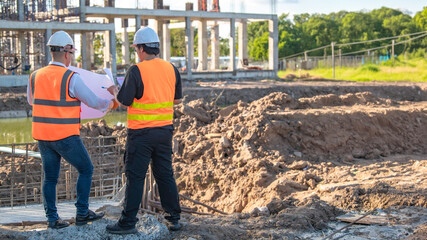 Two Asian engineer working at site of a large building project,Thailand people,Work overtime at construction site,Team of engineer discus at site