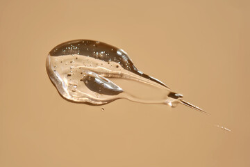A drop of lubricant or cosmetic gel on a beige background.