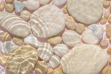 white stones with sun lights shadow in ripple water over abstract pink background, beautiful abstract spa background concept banner for cosmetic body care product