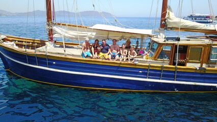Group of people on boat, sailing in Greece and summer sun on ocean holiday, relax in freedom and nature. Yacht vacation, family travel and tropical cruise on sea adventure to Greek island on blue sky