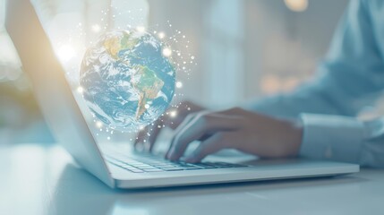 A person is typing on a laptop with a globe in the background