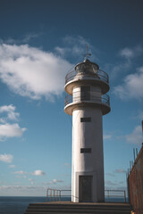 Galician lighthouse on the Atlantic Ocean, standing strong against the rugged coastline with waves crashing below