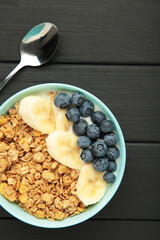 Oat raisin granola with fresh summer berries in a bowl on black background. Vertical photo