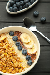 Oat raisin granola with fresh summer berries in a bowl on black background. Concept of healthy breakfast food, clean eating, dieting