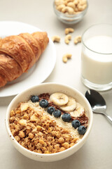 Beautiful morning breakfast with fresh croissants, granola with yoghurt and berries and fruit on plate. Vertical photo