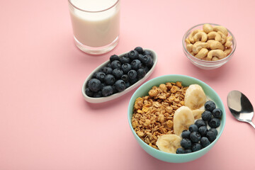 Oat raisin granola with fresh summer berries in a bowl on pink background. Concept of healthy breakfast food, clean eating, dieting