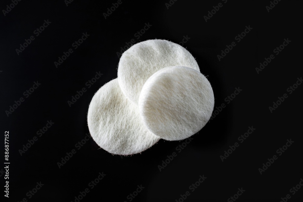 Poster close-up view of three white wool pads lying on a black surface, suitable for various photography an