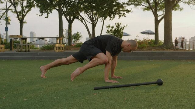 Strong sporty athletic man doing rock climber exercise in public place during sunset,  workout. Plank with alternating knee to elbow. Relaxed workout after work. Warm-up