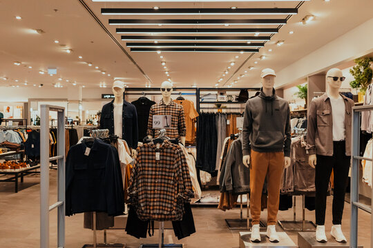A retail shopping store with a lot of clothing and manikins 