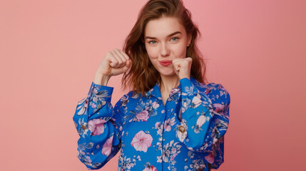 Obraz premium portrait of a woman raising hands in front of pink background