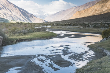 Noisy wide mountain river Panj flows in valley between Afghanistan and Tajikistan in Tien Shan mountains in Pamir in evening