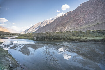 Noisy wide mountain river Panj flows in valley between Afghanistan and Tajikistan in Tien Shan mountains in Pamir in evening