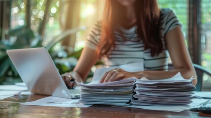 Close-up of professional woman analyzing tax documents on laptop with sunlight in background. Tax day and financial analysis concept.