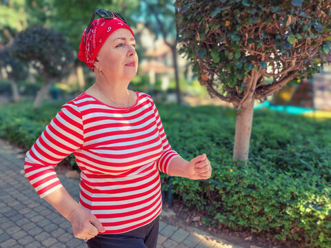 In the morning park, a bald woman wearing a red bandana runs energetically, using her chemotherapy-free days to stay active and combat cancer.