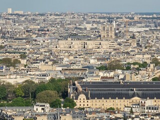 Fototapeta premium Paris, France - April 12, 2024: Aerial view of crowded Paris skyline with Seine River, Ile de France, France. Panorama view from Eiffel tower to the city skylines.