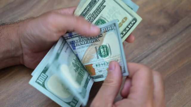 Legal firm managing partner carefully counts dollar banknotes received as part of retainer fee allocating funds to cover ongoing case expenses and firm overheads